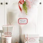 several gifts all wrapped in white paper with red ribbon.